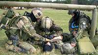 Three service members practise administering first aid to a fourth service member.