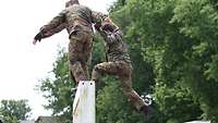 Soldaten überwinden gemeinsam die Hühnerleiter auf der Hindernisbahn