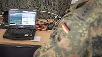 Soldat am Boden sieht das Bild der P-3C am Boden auf seinem Laptop.