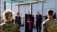 Vier Soldatinnen und Soldaten stehen vor dem Bischof und hören ihm zu.