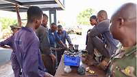 Malische Soldaten im Blaumann reparieren eine Einspritzpumpe. Im Vordergrund steht ein malischer Soldat in Uniform
