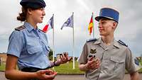 Eine deutsche Soldatin spricht vor Länderfahnen mit einem französischen Kameraden.