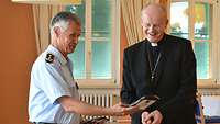 Militärbischof Overbeck bekommt von Dr. Stephan Schmidt ein Präsent überreicht