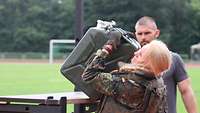 Eine Soldatin stemmt einen schweren Wasserkanister