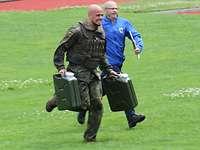 Ein Soldat und ein Schiedsrichter laufen über den Rasen im Sportstadion