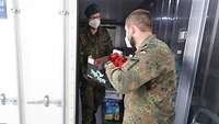 Zwei Soldaten holen Lebensmittelkisten aus einem Kühlcontainer
