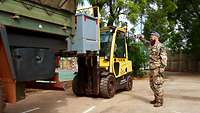 Ein Soldat gibt einem Gabelstaplerfahrer Handzeichen, der gerade einen Lkw entlädt