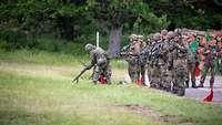 Soldaten in voller Kampfmontur auf dem Truppenübungsplatz. Nach dem Gefechtsschießen entladen sie ihre Gewehre.