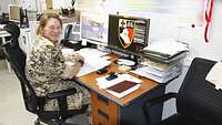 Eine Soldatin sitzt in einem Büro an ihrem Schreibtisch