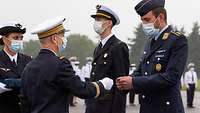 Ein deutscher Hauptmann bekommt von dem französischen Kommandeur eine Anstecknadel mit Wappen verliehen.