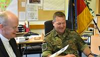 Militärbischhof Overbeck sitz mit dem Stellvertretenden Kommandeur an einem Schreibtisch