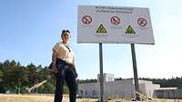 A woman standing next to a sign with several warnings