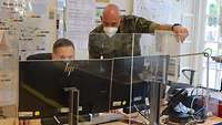 Zwei Soldaten schauen auf einen Monitor und besprechen sich