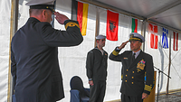 Soldaten in dunkelblauer Marine Uniform grüßen sich.