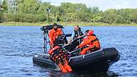 Drei Männer befinden sich auf einem Schlauchboot in See. Zwei davon ziehen eine Person aus dem Wasser ins Boot.