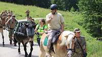 Ein Soldat sitzt auf einem Gebirgspferd, weitere Pferde mit Soldaten folgen. 