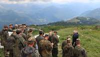 Soldaten stehen auf einer Anhöhe und blicken ins Tal.