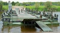 Soldaten bauen mit mehreren Amphibien M3 eine Schwimmbrücke über ein Gewässer