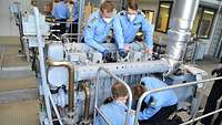 Two soldiers work on an engine.