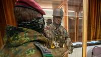 Ein Soldat steht vor einem Glaskasten, in dem eine lebensgroße Puppe steht, die eine alte Uniform trägt.