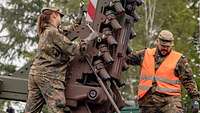 Zwei Soldaten arbeiten an der Verlegevorrichtung eines Panzers.