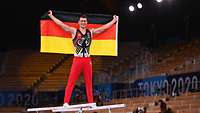 Ein Sportler bei Olympia hält die Deutschlandfahne hoch