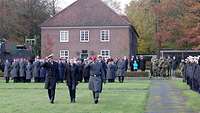 Three men review a parade formation.