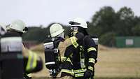 Ein österreichischer Brandschützer prüft das Atemschutzgerät seines deutschen Kameraden.