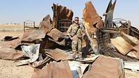 Soldat steht vor einem abgebrannten Wohncontainer, der zu Übungszwecken entzündet wurde