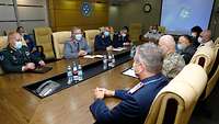 A group of multinational soldiers sits at a large table.