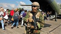 Ein Soldat sichert Zivilpersonen beim Einsteigen in das Transportflugzeug vom Typ C-160 Transall