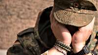 Ein Soldat mit Feldmützte hält beide Hände vor sein Gesicht.