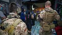 Evakuierte verlassen in Begleitung von Soldaten das Transportflugzeug A400M über die Laderampe am Flughafen in Taschkent