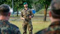 Ein Soldat spricht mit mehreren Soldaten, die in einer Formation vor ihm stehen.