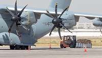 Ein Gabelstapler mit Hilfsgütern steht neben einem Transportflugzeug des Typs A400M am Flughafen von Taschkent