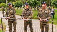 Oberst Marc Vogt, Generalleutnant Ingo Gerhartz und Oberstabsfeldwebel Bratzke zerschneiden symbolisch das Eröffnungsband.