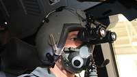 Ein Pilot hat im Cockpit eines A400M einen Helm mit Nachsichtbrille auf.