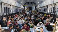 Viele evakuierte Personen sitzen eng aneinander im Laderaum eines Transportflugzeugs vom Typ A400M