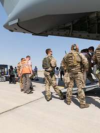Soldaten stehen vor einem Flugzeug aus dem Zivilisten aussteigen
