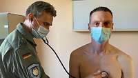 Ein Mann hält mit geschlossenen Augen ein Stethoskop an die nackte Brust des männlichen Patienten.