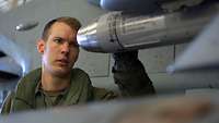 Ein Soldat begutachtet die Bombe an einem Kampfflugzeug