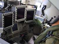 Ein Soldat mit Helm sitzt vor Monitoren in einem Kampfflugzeug