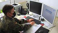 Ein Soldatin sitzt an einem Rechner