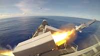 A rocket being launched from a rectangular grey container on the upper deck of a ship.