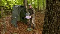 Ein Soldat baut eine Toilettenkabine im Wald auf