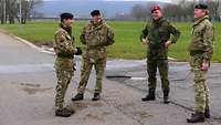 Drei britische und ein deutscher Soldat stehen beieinander und sprechen miteinander.