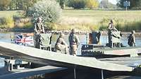 Eine deutsche und eine britische Amphibie M3 sind auf dem Wasser aneinandergekoppelt. Darauf stehen Soldaten.