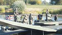 A German and a British amphibious M3 are coupled together on the water. On it stand soldiers.