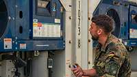Ein Soldat prüft die Einhaltung der Temperatur an der Rückseite eines Kühlcontainers