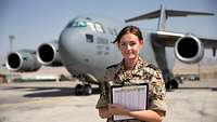 Eine Soldatin steht in Uniform vor einem militärischen FLugzeug